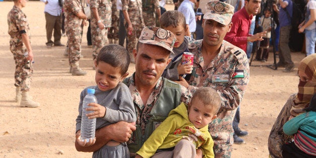 In this Thursday, Sept. 10, 2015 photo, a Jordanian soldier carries Syrian refugee children after they into Jordanian territory with their families, in the Roqban reception area, near the northeastern Jordanian border with Syria, and Iraq, near the town of Ruwaished, 240 km (149 miles) east of Amman. Jordan hosts about 630,000 Syrian refugees, who now make up about 10 percent of the country's population. (AP Photo/Raad Adayleh)