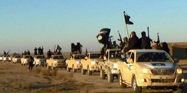 FILE - In this undated file photo released by a militant website, which has been verified and is consistent with other AP reporting, militants of the Islamic State group hold up their weapons and wave its flags on their vehicles in a convoy on a road leading to Iraq, while riding in Raqqa city in Syria. When world leaders convene for the U.N. General Assembly debate Monday, Sept. 28, 2015, it will be a year since the U.S. president declared the formation of an international coalition to "degrade and ultimately destroy" the Islamic State group. Despite billions of dollars spent and thousands of airstrikes, the campaign appears to have made little impact. (Militant website via AP, File)