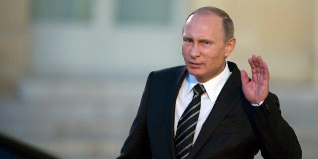 Russian President Vladimir Putin holds his hand on his ear while listening to a newsmanâs question as he leaves the Elysee