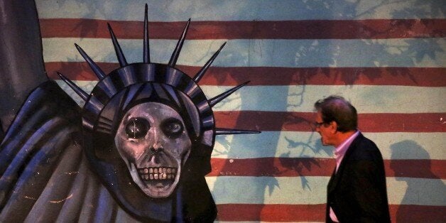 A man walks past a satirized painting of the Statue of Liberty painted on the wall of the former U.S. Embassy, in Tehran, Ira