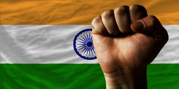 complete national flag of india covers whole frame, waved, crunched and very natural looking. In front plan is clenched fist symbolizing determination