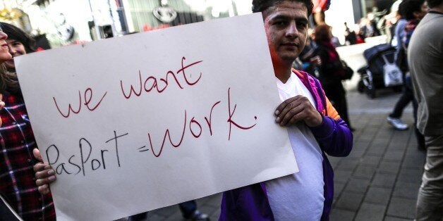 A protester holds a banner reading 'we want passport = work' during a pro-aylum demo to welcome refugees in Vienna on Oktober 3, 2015. In recent months Austria has become a major transit country for tens of thousands of migrants entering from Hungary -- having travelled up through the western Balkans -- bound for northern Europe, in particular Germany. The banner reads 'refugees in. FPO out'. AFP PHOTO / PATRICK DOMINGO (Photo credit should read PATRICK DOMINGO/AFP/Getty Images)