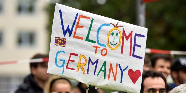 People welcome refugees with a banner reading 'welcome to Germany' in Dortmund, Germany, Sunday, Sept. 6, 2015, where thousands of migrants and refugees arrived by trains. (AP Photo/Martin Meissner)