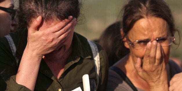 Mourners, one wearing a picture of Ayse Deniz, one of the victims of Saturday's Ankara bombing attacks, cry during a funeral in Izmir, Turkey, Monday, Oct. 12, 2015. Turkish investigators are close to identifying one of the suicide bombers in Turkey's deadliest attacks in years, Prime Minister Ahmet Davutoglu said Monday. (AP Photo/Emre Tazegul)