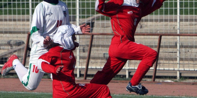 FILE - In this Friday, April 28, 2006 file photo, Berlin's female soccer team player, Valerie Assmann, right, fights for the ball in front of her unidentified teammate and Iranian women soccer team player, Niloufar Ardalan, left, during their friendly match at the Ararat stadium in Tehran, Iran. Iranian womenâs soccer captain Ardalan reportedly will miss the Asian Cup tournament as her husband has confiscated her passport in a domestic quarrel, according to a report by he Iranian news website fararu.com on Monday, Sept. 16, 2015.(AP Photo)