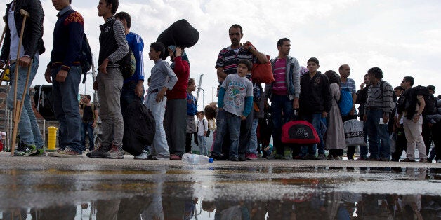Migrants and refugees wait for a bus after their arrival with a ferry from the Greek island of Lesbos at the Athens' port of