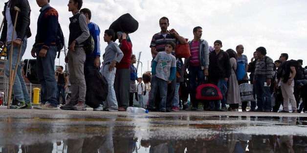 Migrants and refugees wait for a bus after their arrival with a ferry from the Greek island of Lesbos at the Athens' port of Piraeus, on Thursday, Oct. 8, 2015. The U.N. refugee agency UNHCR estimates 396,500 people have entered Greece via the Mediterranean this year with seventy percent of them are from war-torn Syria. (AP Photo/Petros Giannakouris)