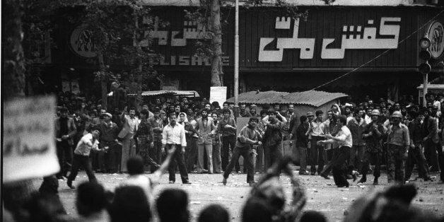 Tehran, Iran: Hezbollah forces (plain clothes pro-government) standing between Revolutionary Guards armed with machine guns, attack leftist students with rocks and stones, in street clashes outside Tehran university, on the occasion of Cultural Revolution, 21st April 1981. The Cultural Revolution (1980-1987) was a period following the 1979 Islamic Revolution in Iran where the academia of Iran was purged of Western and non-Islamic influences to bring it in line with Shia Islam. The official name used by the Islamic Republic is 'Cultural Revolution.' Directed by the Cultural Revolutionary Headquarters and later by the Supreme Cultural Revolution Council, the revolution initially closed universities for three years (1980-1983) and after reopening banned many books and purged thousands of students and lecturers from the schools. The cultural revolution involved a certain amount of violence in taking over the university campuses since higher education in Iran at the time was dominated by leftists forces opposed to Ayatollah Khomeini's vision of theocracy, and they (unsuccessfully) resisted Khomeiniist control at many universities. (Photo by Kaveh Kazemi/Getty Images)