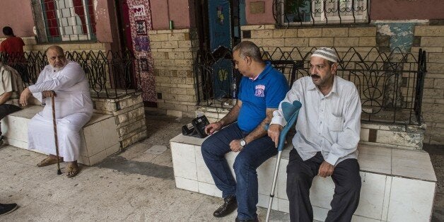 An Egyptian official (C) searches on electronic device for the name of a voter (R) at a polling station in Cairo's Giza distr