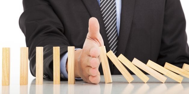 businessman hand stop dominoes continuous toppled on the desk