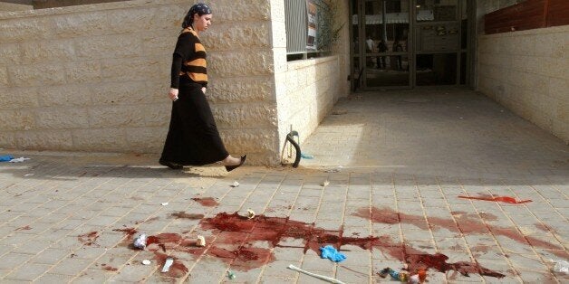 An Israeli Jewish woman walks past a site where two alleged Palestinian attackers were shot by Israeli police after attempting to board a bus carrying children then stabbing an Israeli man, in the Israeli city of Beit Shemesh, west of Jerusalem, on October 22, 2015. The two men were blocked from entering the bus in Beit Shemesh by the driver and others. They then stabbed and moderately wounded a 25-year-old Israeli man near the bus station, according to police spokesman Micky Rosenfeld. AFP PHOTO / GIL COHEN-MAGEN (Photo credit should read GIL COHEN MAGEN/AFP/Getty Images)