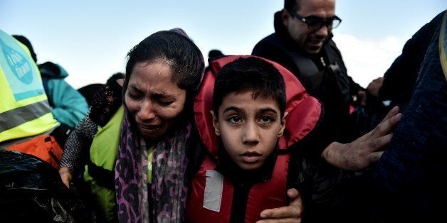 A woman, holding her child, cries as she arrives, with other refugees and migrants on the Greek island of Lesbos on October 2