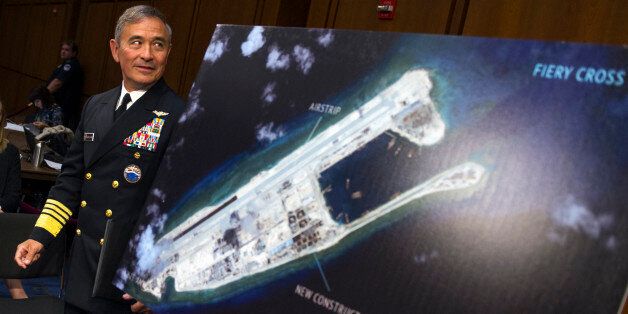 FILE - In this Sept. 17, 2015 file photo, Adm. Harry B. Harris, Jr. of U.S. Navy Commander, U.S. Pacific Command walks past a photograph showing an island that China is building on the Fiery Cross Reef in the South China Sea, as the prepares to testify on Capitol Hill in Washington. As expectations grow that the U.S. Navy will directly challenge Beijingâs South China Sea claims, China is engaging in some serious image-building for its own military by hosting two international security forums beginning Friday, Oct. 16, 2015. (AP Photo/Cliff Owen, File)