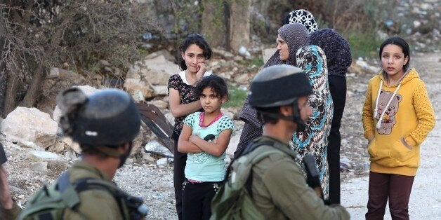 Israeli security forces stand and Palestinians gather at the scene where a Palestinian attempted to stab an Israeli soldier before being shot dead in the occupied West Bank city of Hebron on October 28, 2015. The United Nations warned that a deadly surge in violence between Israelis and Palestinians was headed toward 'catastrophe' as new knife attacks took place in the volatile West Bank. AFP PHOTO / HAZEM BADER (Photo credit should read HAZEM BADER/AFP/Getty Images)