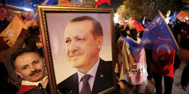 A supporter of the Justice and Development Party, (AKP), holds a portrait of Turkey's President Recep Tayyip Erdogan as people celebrate outside the AKP headquarters, in Istanbul, Turkey, late Sunday, Nov. 1, 2015. Turkey's ruling party secured a stunning victory in Sunday's snap parliamentary election, sweeping back into single-party rule only five months after losing it. The preliminary result, reported after nearly 99 percent of votes were counted, would show the ruling Justice and Development Party (AKP) had won more than 49 percent of the vote and was projected to get 316 seats in parliament, in a stunning victory. (AP Photo/Emrah Gurel)