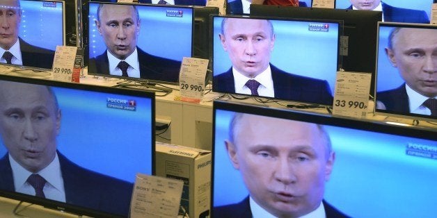 An employee walks past TV screens in a shop in Moscow, on April 17, 2014, during the broadcast of President Vladimir Putin's