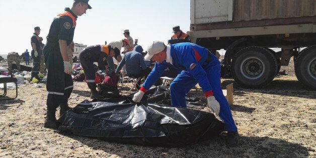 In this Russian Emergency Situations Ministry photo, made available on Tuesday, Nov. 3, 2015 Russian Emergency employees collect personal belongings of a plane crash victims at the crash site of a passenger jet bound for St. Petersburg in Russia that crashed in Hassana, Egypt, on Monday, Nov. 2, 2015. The Russian cargo plane on Monday brought the first bodies of Russian victims killed in a plane crash in Egypt home to St. Petersburg, a city awash in grief for its missing residents. (Russian Ministry for Emergency Situations photo via AP)