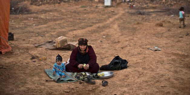 A Syrian refugee child sits next to his grandmother while peeling aubergine for dinner, outside their tent at an informal tented settlement near the Syrian border on the outskirts of Mafraq, Jordan, Wednesday, Oct. 28, 2015. (AP Photo/Muhammed Muheisen)