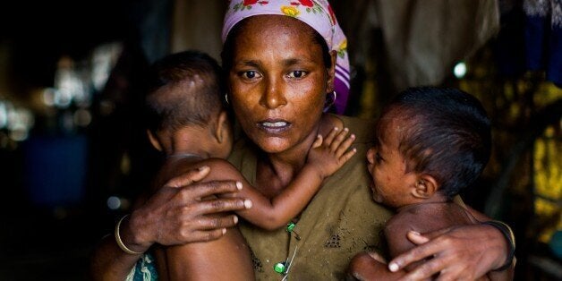 SITTWE , MYANMAR - JULY 17 : A distressed mother named Shamijder (age 30) holds onto her twins aged 1 year whom both suffer from malnutrition in Sittwe, Rakhine State Myanmar on July 17 2015. An estimated 110,000 ethnic Rohingya live in an overcrowded IDP camp in the outskirts of Sittwe. The Rohingya continually make attempts to flee the camps by fishing boat and seek asylum in neighbouring Islamic countries however often fall victim to human traffickers. At current they are a stateless people believed to be illegal immigrants from Bangladesh. According to the UN the Rohingya are one of the most persecuted minorities in the world. (Photo by Asanka Brendon Ratnayake/Anadolu Agency/Getty Images)