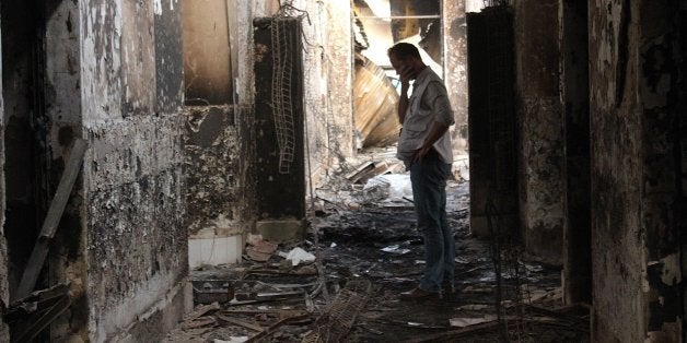 In this Friday, Oct. 16, 2015 photo, an employee of Doctors Without Borders walks inside the charred remains of their hospita