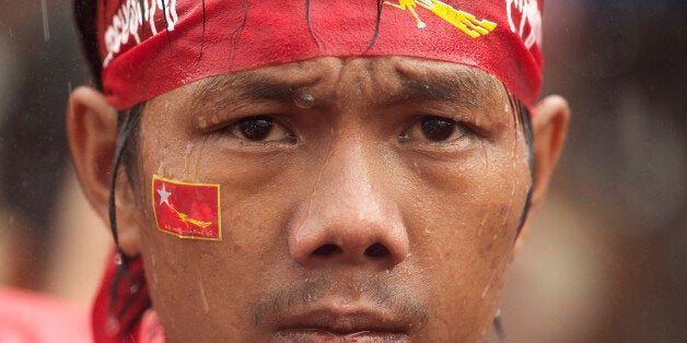 A supporter of Myanmar's National League for Democracy party waits in pouring rain outside the NLD headquarters in Yangon, Myanmar, Monday, Nov. 9, 2015. Opposition leader Aung San Suu Kyi's NLD party said Monday that it was confident it was headed for a landslide victory in Myanmar's historic elections, and official results from the government that began trickling in appeared to back up the claim. (AP Photo/Mark Baker)