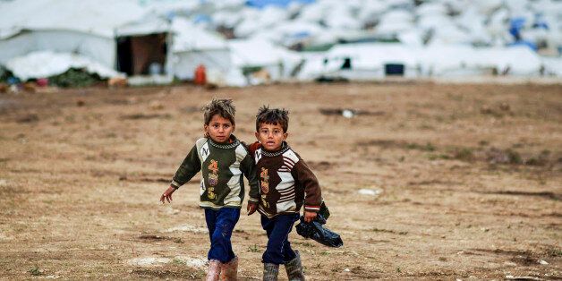 Syrian boys, whose family fled their home in Idlib, walk to their tent, at a camp for displaced Syrians, in the village of Atmeh, Syria, Monday, Dec. 10, 2012