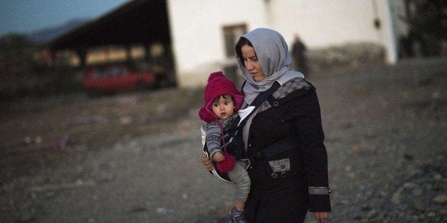 A woman and her daughter wait along with other migrants and refugees to enter a registration camp after crossing the Greek-Macedonian border near Gevgelija on November 9, 2015. The heads of state and government from most of the EU member countries and more than 30 African nations are due in the Maltese capital Valletta on November 11 for talks on tackling Europe's migration crisis. AFP PHOTO / ROBERT ATANASOVSKI (Photo credit should read ROBERT ATANASOVSKI/AFP/Getty Images)