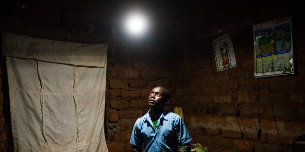 Erasmus Wambua, a schoolboy, looks at a single electric lightbulb, powered by M-Kopa solar technology, as it illuminates his home in Ndela village, Machakos county, in Kenya, on Wednesday, July 22, 2015. Customers agree to pay for the solar panel with regular instalments which M-Kopa, a Nairobi-based provider of solar-lighting systems, then monitors for payments that are made using a mobile-phone money-transfer service. Photographer: Waldo Swiegers/Bloomberg via Getty Images