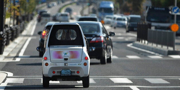 A Toyota Auto Body Co. Coms super-compact electric vehicle (EV) drives along a road in the Higashiyama district of Toyota Cit