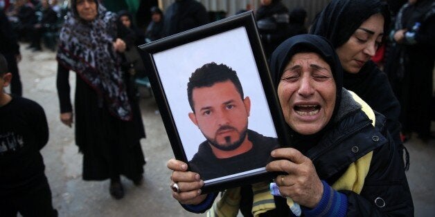 A relative of Samer Huhu, who was killed in a twin bombing attack that rocked a busy shopping street in the area of Burj al-Barajneh, waves his portrait as she mourns during his funeral in the southern suburb of the capital Beirut on November 13, 2015. Lebanon mourned 44 people killed in south Beirut in a twin bombing claimed by the Islamic State group, the bloodiest such attack in years, the Red Cross also said at least 239 people were also wounded, several in critical condition. AFP PHOTO/JOSEPH EID (Photo credit should read JOSEPH EID/AFP/Getty Images)