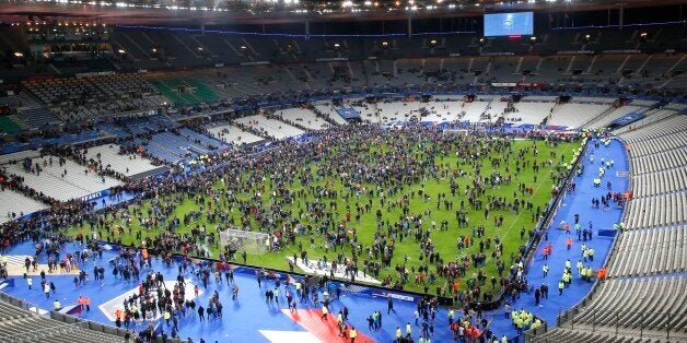 Spectators invade the pitch of the Stade de France stadium after the international friendly soccer France against Germany, Friday, Nov. 13, 2015 in Saint Denis, outside Paris. At least 35 people were killed in shootings and explosions around Paris, many of them in a popular theater where patrons were taken hostage, police and medical officials said Friday. Two explosions were heard outside the Stade de France stadium. (AP Photo/Michel Euler)