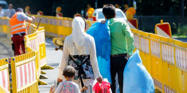 Asylum seekers walk outside the central refugee camp in Giessen, Germany, Monday, Aug. 3, 2015. (AP Photo/Michael Probst)