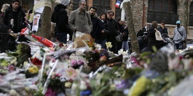 People spend a moment mourning the dead at the site of the attack at the Cafe Belle Equipe on rue de Charonne, prior to going to work early on November 16, 2015 in Paris, three days after the terrorist attacks that left over 130 dead and more than 350 injured. France prepared to fall silent at noon on November 16 to mourn victims of the Paris attacks after its warplanes pounded the Syrian stronghold of Islamic State, the jihadist group that has claimed responsibility for the slaughter. AFP PHOTO / KENZO TRIBOUILLARD (Photo credit should read KENZO TRIBOUILLARD/AFP/Getty Images)