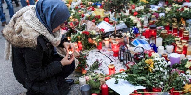BERLIN, GERMANY - NOVEMBER 16: A young Muslim woman lights a candle outside the French Embassy among candles, messages and f