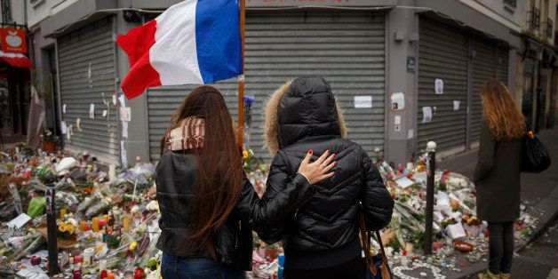 Two women stand outside the Petit Cambodge restaurant, a site of last Friday's attacks, in Paris, Tuesday, Nov. 17, 2015. France made an unprecedented demand on Tuesday for its European Union allies to support its military action against the Islamic State group as it launched new airstrikes on the militants' Syrian stronghold, days after attacks in Paris linked to the group killed at least 129 people. (AP Photo/Daniel Ochoa de Olza)