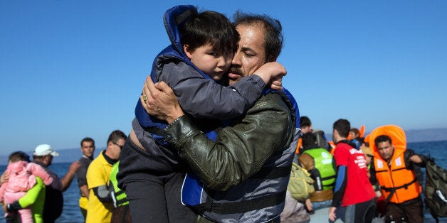 SIKAMINIAS, GREECE - NOVEMBER 12: A boy is carried ashore as a migrant boat lands after making the crossing from Turkey to t