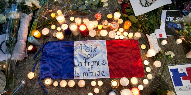 A flag of France is surrounded by candles and flowers outside of the French embassy in Mexico City during a vigil for the vic