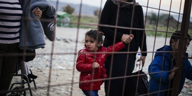 ? woman and her crying child walk along with other migrants and refugees as they wait to enter a registration camp after cros