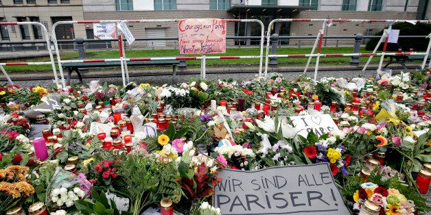 Flowers are placed in front of the embassy of France close to the Brandenburg Gate in Berlin, Germany, Monday, Nov. 16, 2015, to honor the victims of the terrorist attacks in France on Friday, Nov. 13, 2015. Multiple attacks across Paris on Friday night have left scores dead and hundreds injured. Text on poster reads 'We are all Parisians'. (AP Photo/Michael Sohn)