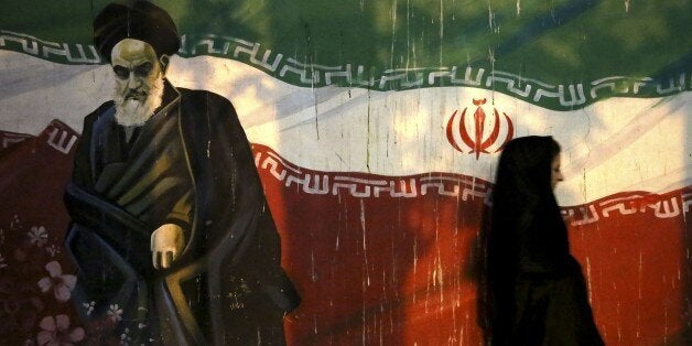 FILE - In this Nov. 2, 2013 file photo, a veiled Iranian woman walks past a mural depicting the late revolutionary founder Ayatollah Khomeini, and national Iranian flag, painted on the wall of the former U.S. Embassy, in Tehran, Iran. Siamak Namazi, an Iranian-American businessman who advocated better ties between Iran and the U.S. reportedly has been arrested and imprisoned in Tehran, becoming the fourth U.S. citizen known to be held there at a time when hard-liners are pushing back against the country's nuclear deal with world powers. Iranian officials could not be reached for comment Friday, Oct. 30, 2015, part of the Iranian weekend, and state media did not report on Namazi's reported detention. (AP Photo/Ebrahim Noroozi)