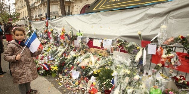 PARIS, FRANCE - NOVEMBER 27: People with the French Tricolore flag at the 'Bataclan' concert hall in memory of the 130 victims of the Paris terrorist attacks on November 27, 2015 in Paris, France. French President Francois Hollande called on all French citizens to hang the tricolore national flag from their windows to pay tribute to the victims of the terrorist attacks. (Photo by Patrick Aventurier/Getty Images)