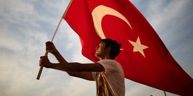 A man waves a national flag as thousands of people march to protest against the deadly attacks on Turkish troops, in Izmir, T