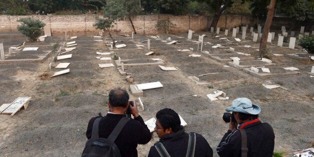 Pakistani news photographers take pictures of desecrated graves at the minority Ahmadi sect graveyard in Lahore on December 3, 2012. Gunmen desecrated graves of Ahmadis in eastern Pakistan, members of the minority community said, in the latest act of intimidation and religious hatred against the beleaguered group. AFP PHOTO/Arif ALI (Photo credit should read Arif Ali/AFP/Getty Images)