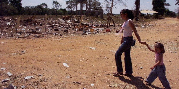 Residents walk amid the remains of La Union, 100 miles southeast of Villavicencio, Colombia, in this Jan. 21, 2003 photo, after a bomb exploded. A half-ton bomb was hidden by guerillas in a house in this village for more than a month, with the intent to detonate the bomb by remote control whenever an army patrol passed through. On Jan. 19, someone tipped of the army, which then detonated the bomb after not being able to deactivate it, leaving a 3-foot-deep crater in the village and collapsing homes for 300 feet in every direction. (AP Photo/Juan Herrera)