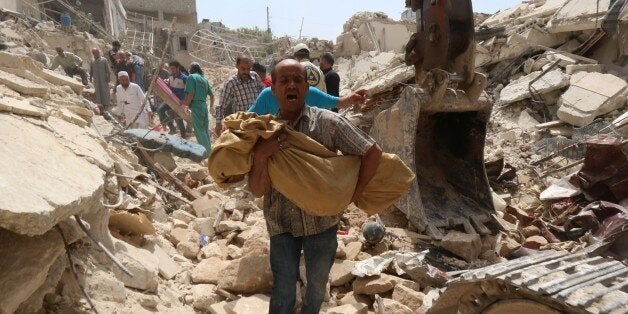 A Syrian man carries a body after it was removed from the rubble of buildings following a reported barrel bomb attack by gove