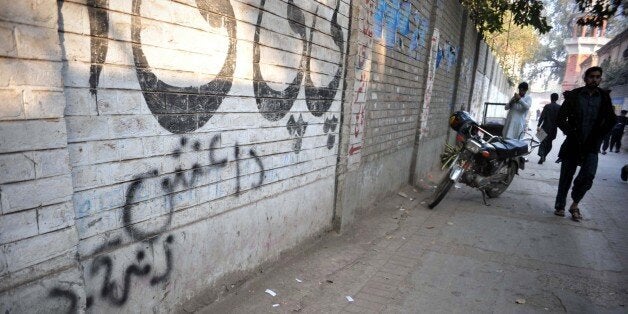 A Pakistani pedestrian walks past wall graffiti (bottom) which reads Daesh, the arabic acronym for Islamic State (IS), in Peshawar on November 22, 2014. The Islamic State organisation is starting to attract the attention of radicals in Pakistan and Afghanistan, long a cradle for Islamist militancy, unnerving authorities who fear a potential violent contagion. AFP PHOTO/A MAJEED (Photo credit should read A Majeed/AFP/Getty Images)