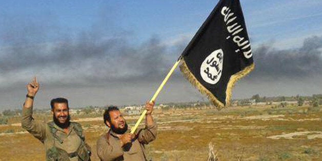 FILE - In this file photo released on Sunday, June 28, 2015, by a website of Islamic State militants, an Islamic State militant waves his group's flag as he and another celebrate in Fallujah, Iraq, west of Baghdad.The Islamic Stateâs gruesome rampage across the Middle East has united the world in horror but left it divided over how to refer to the group, with observers adopting different acronyms based on their translation of an archaic geographical term and the extent to which they want to needle the group. (Militant website via AP, File)