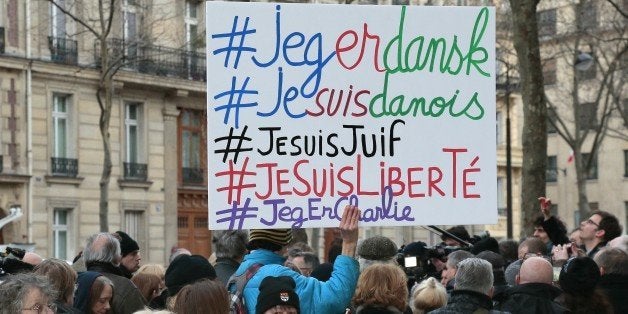 A man holds a placard with the hashtags 'I am Danish, I am Jewish, I am Freedom' next to a woman holding a Danish flag outside the Danish Embassy in Paris on February 16, 2015, where France's political leaders attended a commemorative gathering after double shootings that killed two people at a cultural centre and a synagogue in Copenhagen on February 14. The twin attacks on a cultural centre and synagogue in Copenhagen left two people dead and five police officers wounded before the assailant himself was gunned down. AFP PHOTO / JACQUES DEMARTHON (Photo credit should read JACQUES DEMARTHON/AFP/Getty Images)