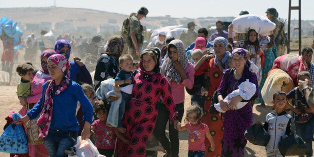 Syrian refugee women and children gather at the border in Suruc, Turkey, Saturday, Sept. 20, 2014. TSeveral thousand Syrians,