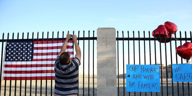 SAN BERNARDINO, CA - DECEMBER 04: Ernesto Vasquez hangs an American flag at a makeshift memorial near the Inland Regional Center on December 4, 2015 in San Bernardino, California. The FBI has officially labeled the attack carried out by Syed Farook and his wife Tashfeen Malik as an act of terrorism. The San Bernardino community continues to mourn the attack at the Inland Regional Center in San Bernardino that left at least 14 people dead and another 21 injured. (Photo by Justin Sullivan/Getty Images)